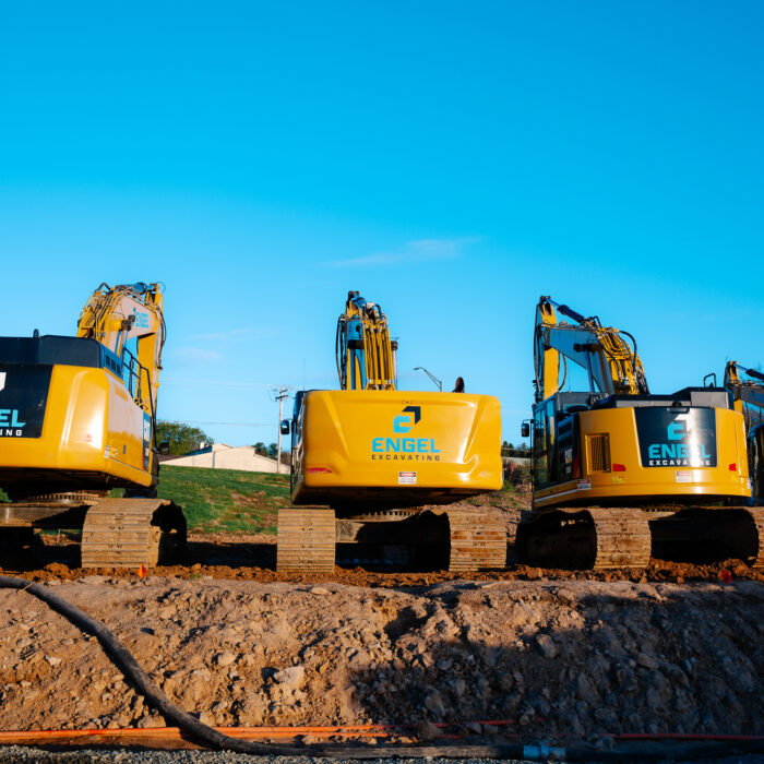 Four yellow Engel Excavating excavators on a dirt lot.