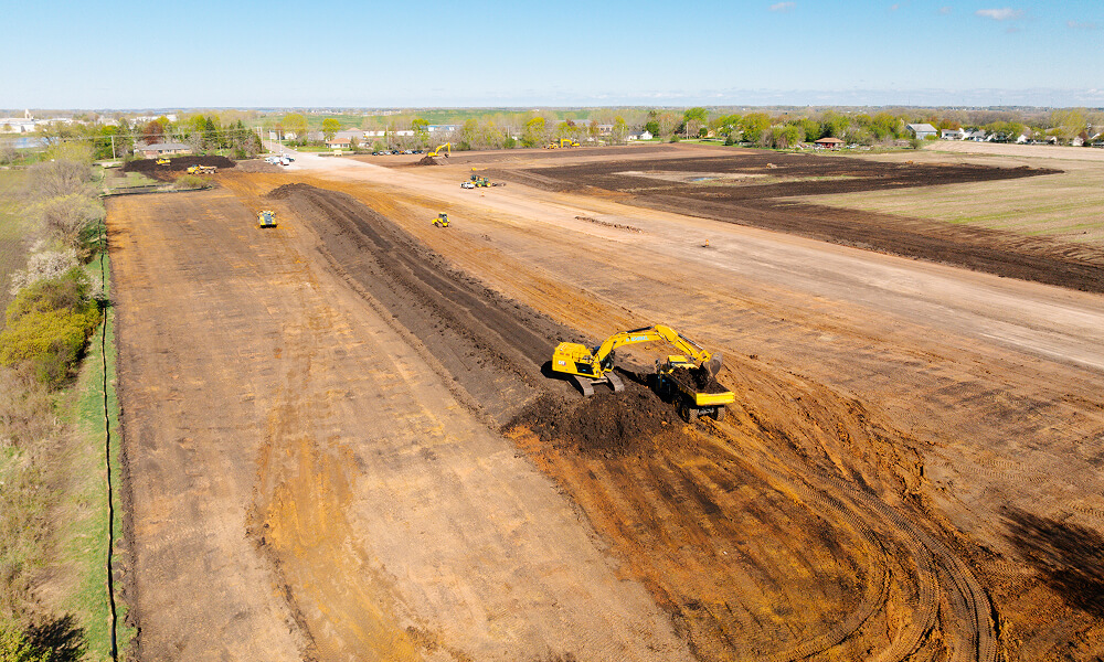 Machines moving soil at large construction site, aerial view.