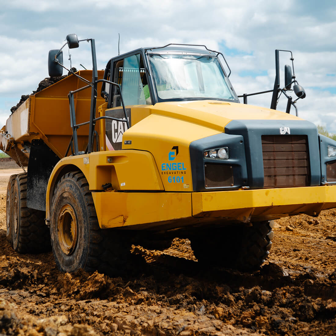 Engel Excavating dump truck loaded with dirt on muddy site.