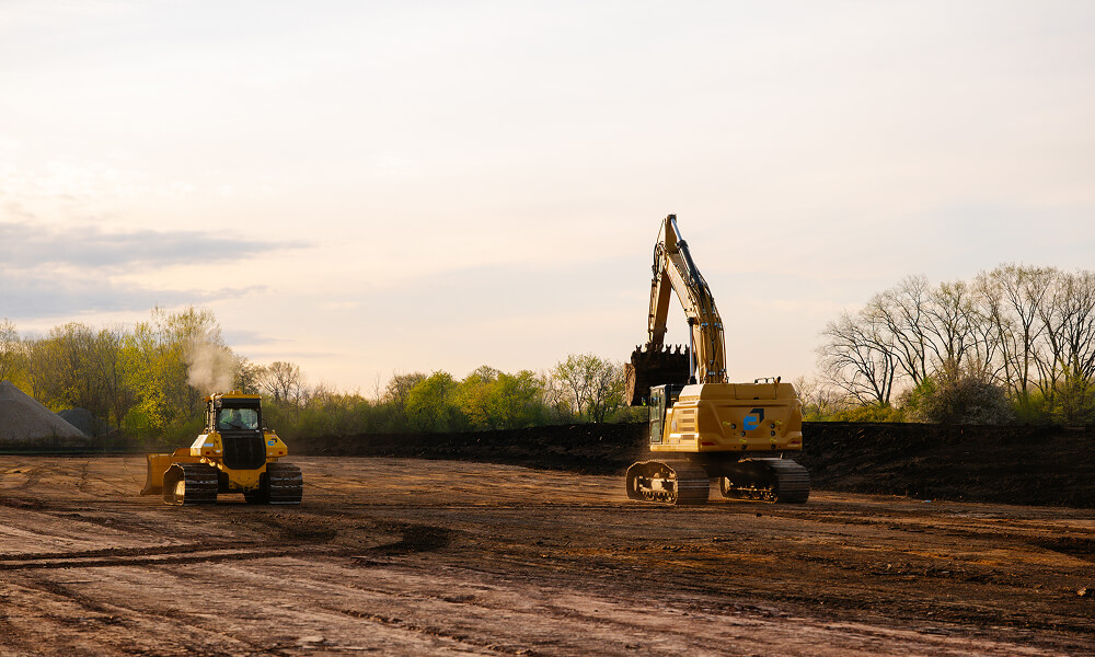 Bulldozer and excavator at a dirt construction site.