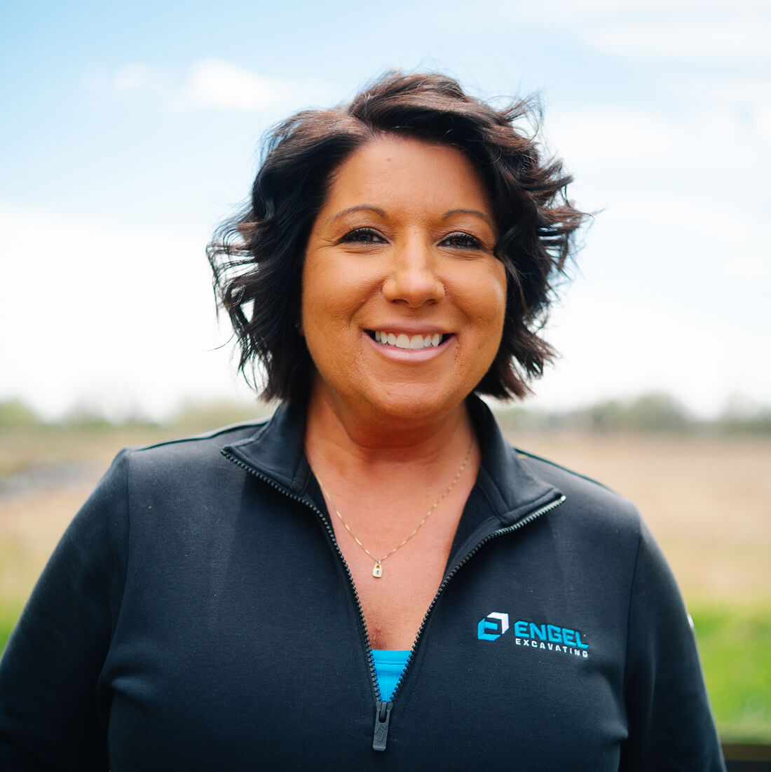 Smiling woman outdoors in Engel Excavating jacket.