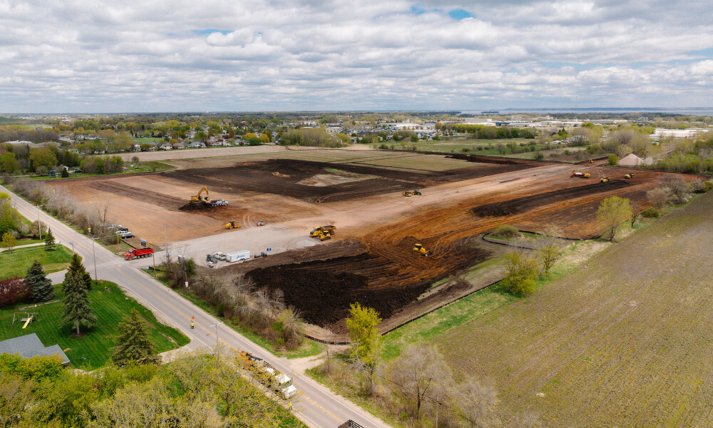 Aerial view of construction site with trucks and trees.